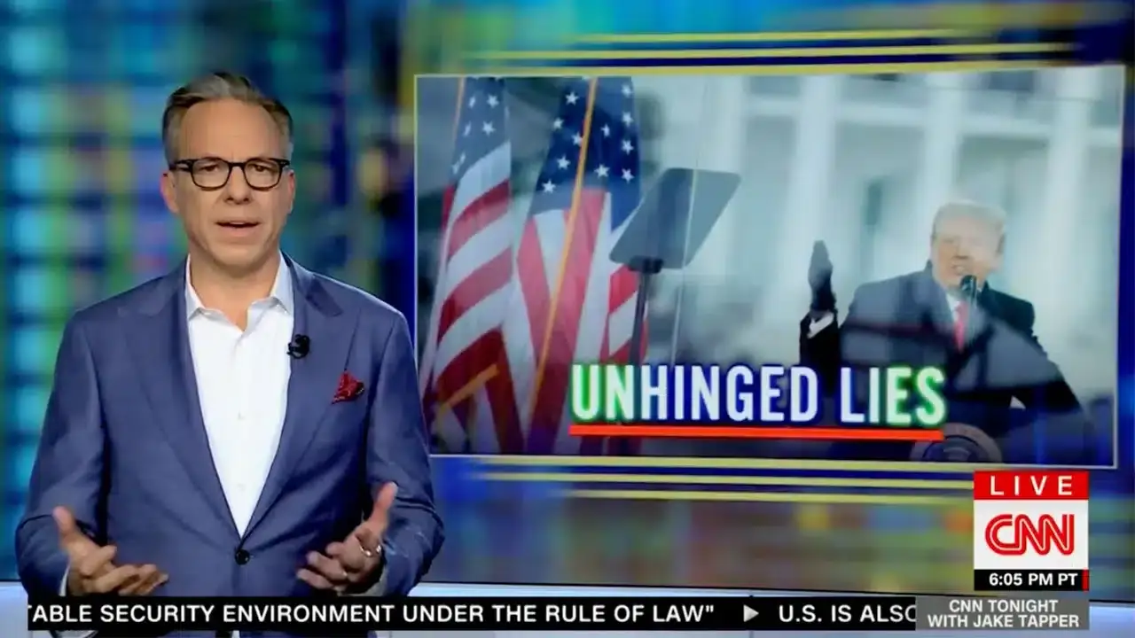 News anchor in a studio with a screen displaying a U.S. flag, a podium, and a blurred figure. The text reads "Unhinged Lies.